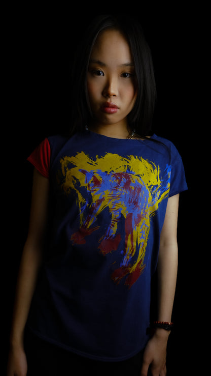 A young woman with long black hair wearing our Cats tee, a dark navy blue graphic t-shirt with a colorful abstract cat print, posed against a solid black background.